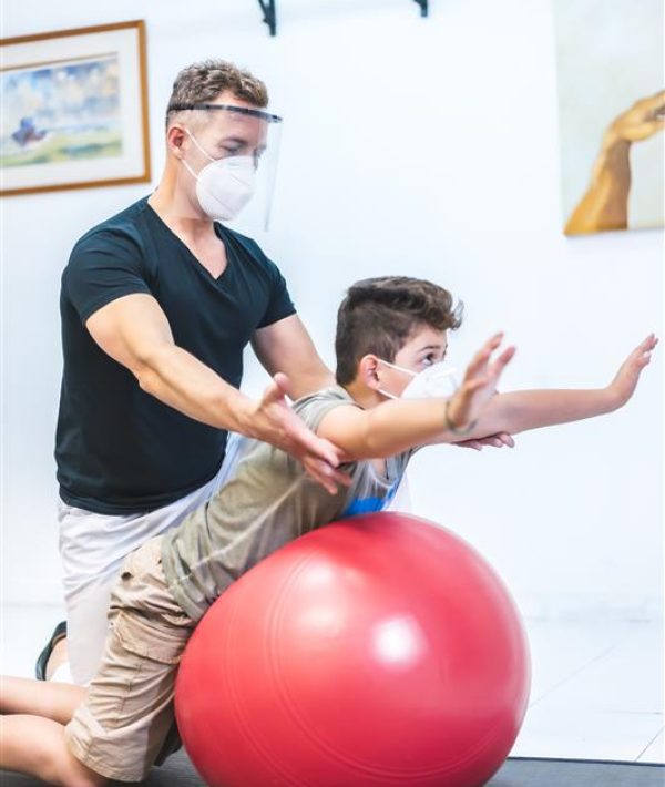 physiotherapist-with-mask-screen-doing-back-stretches-child-opening-with-security-measures-physiotherapists-covid-19-pandemic-osteopathy-therapeutic-chiromassage physiotherapist-with-mask-screen-doing-back-stretches-child-opening-with-security-measures-physiotherapists-covid-19-pandemic-osteopathy-therapeutic-chiromassage